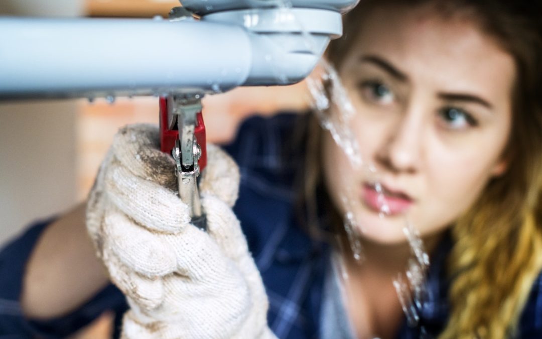 woman fixing a leaking drain pipe in home